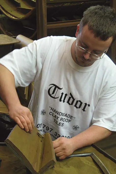 A Tudor craftsman pressing clay into a tile mould