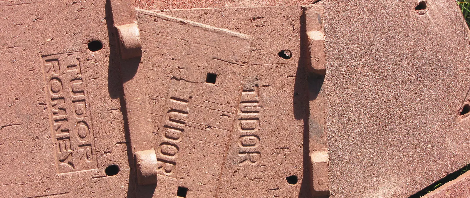 The backs of handmade tiles stamped Tudor and Romney